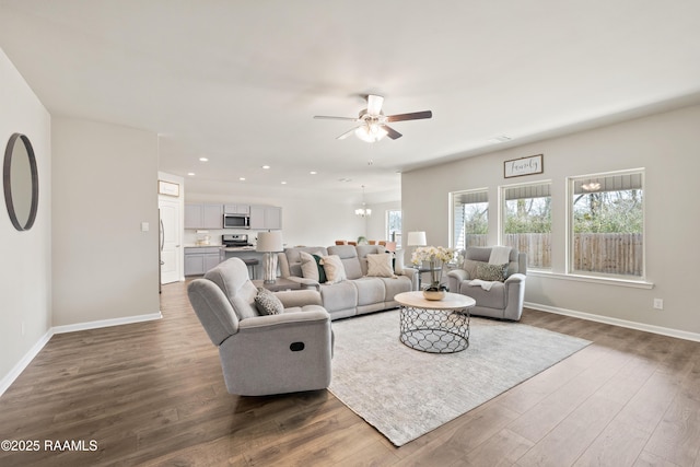 living area featuring ceiling fan with notable chandelier, recessed lighting, wood finished floors, and baseboards