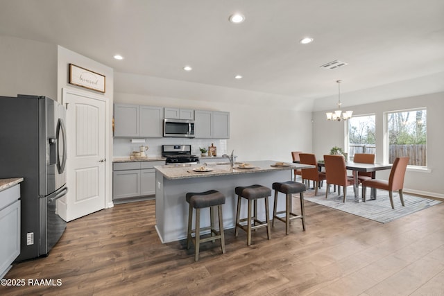 kitchen featuring stainless steel appliances, dark wood-style flooring, visible vents, gray cabinets, and light stone countertops