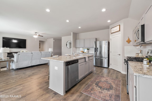 kitchen featuring tasteful backsplash, dark wood finished floors, light stone counters, stainless steel appliances, and gray cabinetry