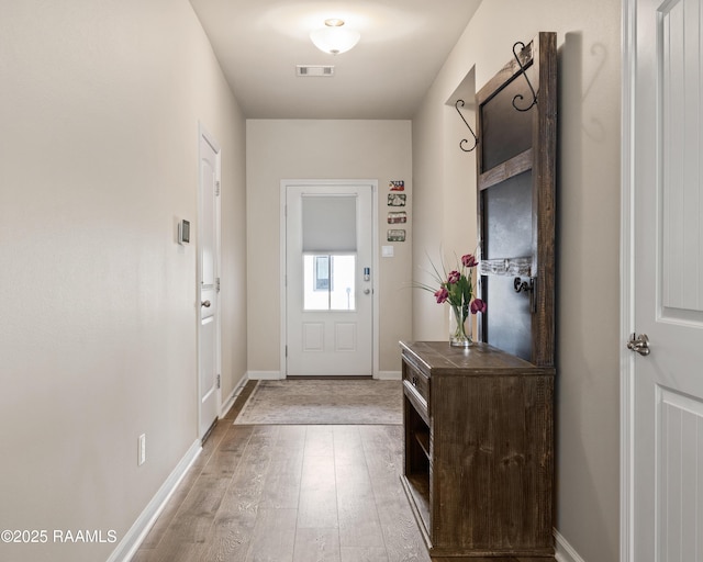 doorway with light wood-type flooring, baseboards, and visible vents