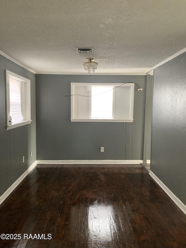 spare room featuring crown molding, dark wood-type flooring, and a textured ceiling