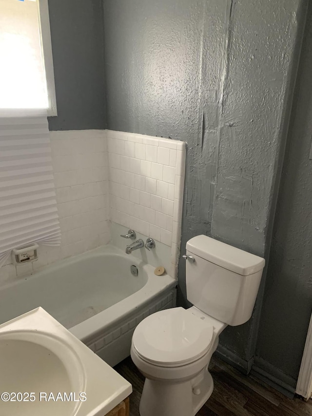 bathroom with a bathing tub, wood-type flooring, vanity, and toilet