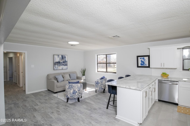 kitchen featuring a breakfast bar, white cabinets, ornamental molding, stainless steel dishwasher, and kitchen peninsula