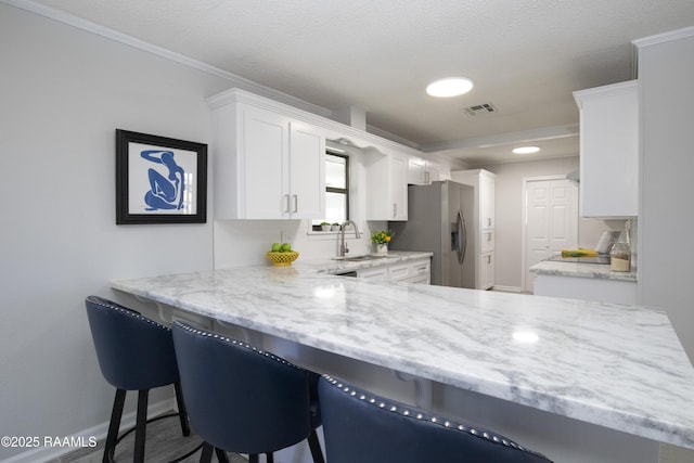 kitchen featuring sink, kitchen peninsula, white cabinets, and a kitchen bar