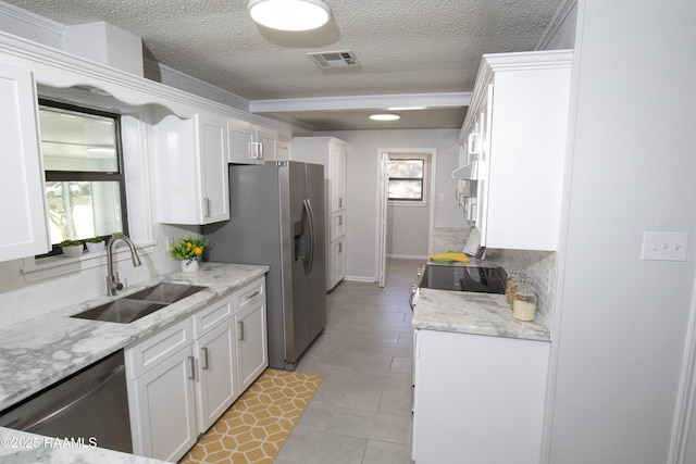 kitchen with sink, white cabinets, backsplash, stainless steel appliances, and light stone countertops