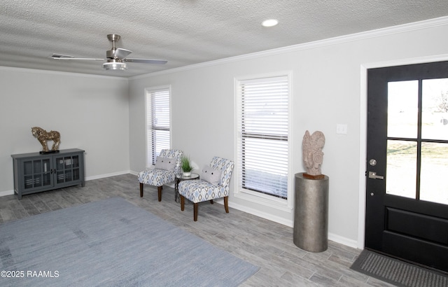 entryway with a wealth of natural light, ornamental molding, a textured ceiling, and light wood-type flooring