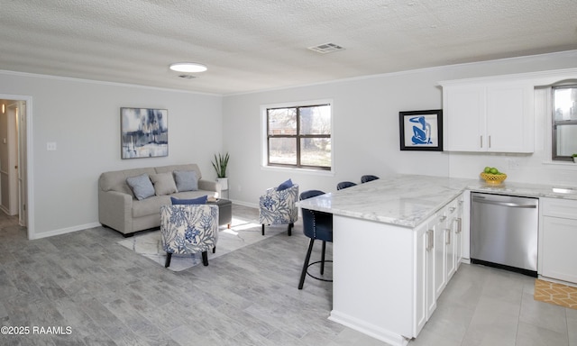 kitchen featuring a breakfast bar, dishwasher, white cabinets, ornamental molding, and kitchen peninsula