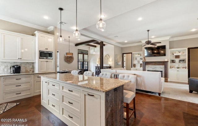 kitchen featuring stainless steel microwave, decorative light fixtures, a breakfast bar, a fireplace, and a ceiling fan