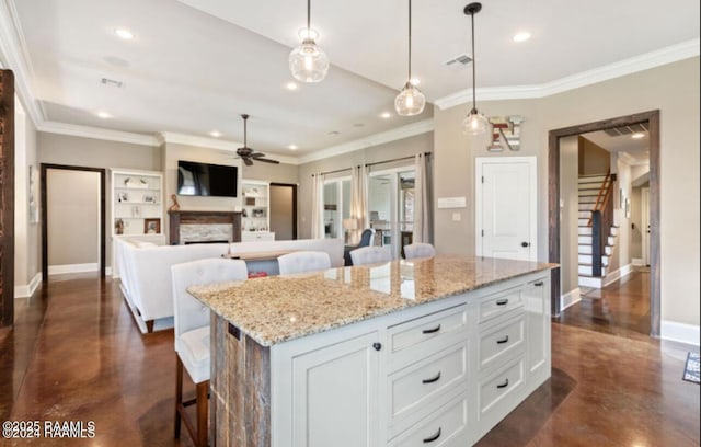 kitchen featuring a kitchen bar, visible vents, white cabinets, a fireplace, and baseboards