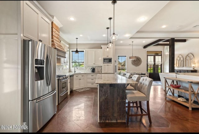 kitchen with light stone counters, a kitchen island, a sink, decorative backsplash, and appliances with stainless steel finishes