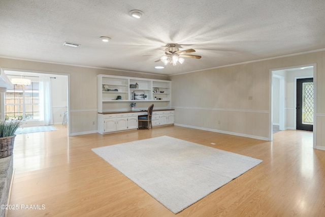 unfurnished living room featuring light hardwood / wood-style flooring, built in desk, ornamental molding, and a textured ceiling