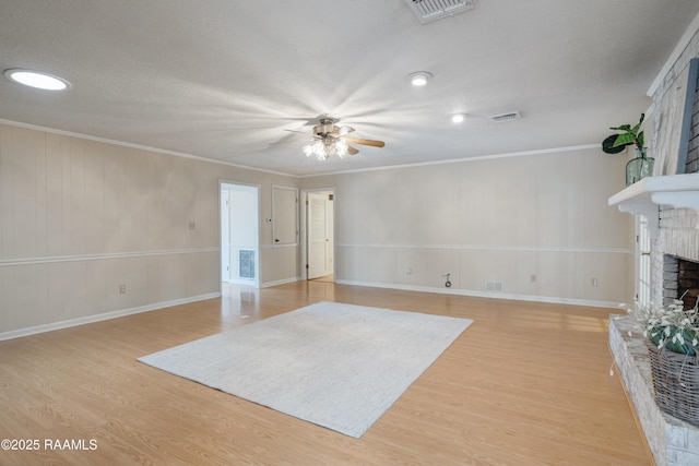 living room featuring ornamental molding, a fireplace, light hardwood / wood-style floors, and ceiling fan