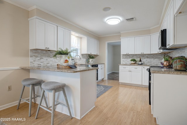 kitchen with light hardwood / wood-style flooring, light stone countertops, white cabinets, and a kitchen bar