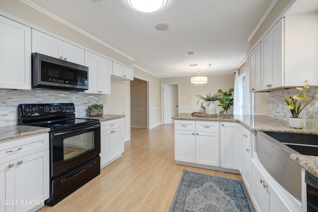 kitchen featuring white cabinetry, black electric range, kitchen peninsula, pendant lighting, and light hardwood / wood-style floors