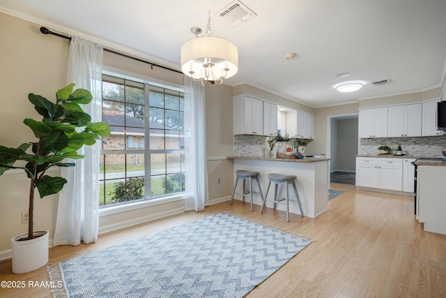 kitchen with white cabinetry, crown molding, light wood-type flooring, kitchen peninsula, and electric stove