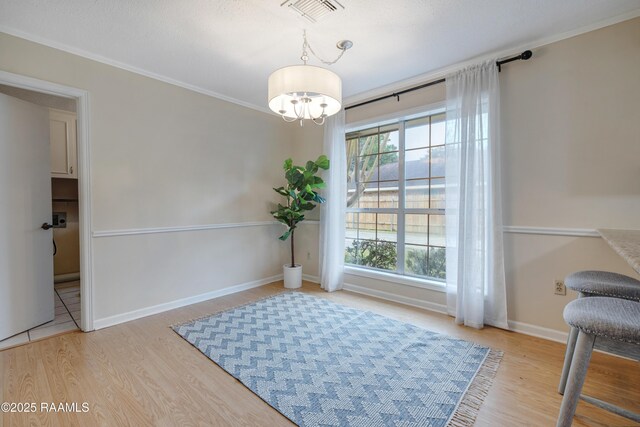 sitting room with ornamental molding, an inviting chandelier, and light hardwood / wood-style flooring