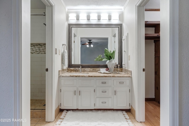 bathroom featuring crown molding, tiled shower, vanity, and a textured ceiling