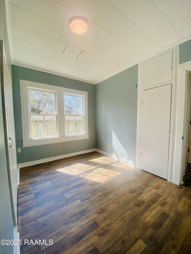 unfurnished bedroom with ornamental molding and dark wood-type flooring