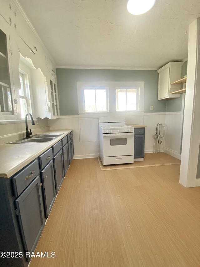 kitchen featuring sink, light hardwood / wood-style flooring, gray cabinetry, white cabinets, and white range