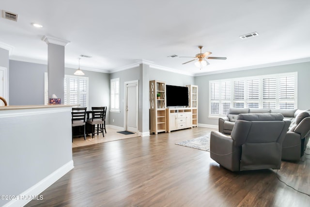 living room featuring ceiling fan, dark wood-type flooring, a healthy amount of sunlight, and ornate columns