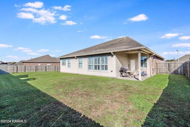 rear view of property featuring a yard and a patio area