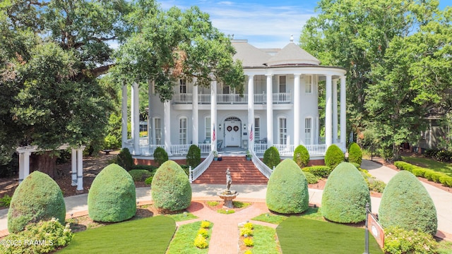 view of front of property featuring a front lawn, a balcony, and covered porch