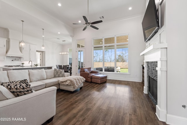 living room with ornamental molding, dark wood-type flooring, sink, and ceiling fan