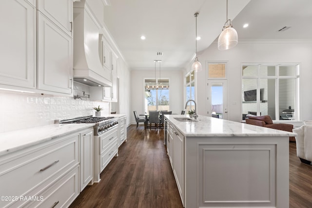 kitchen with hanging light fixtures, white cabinetry, a kitchen island with sink, and sink