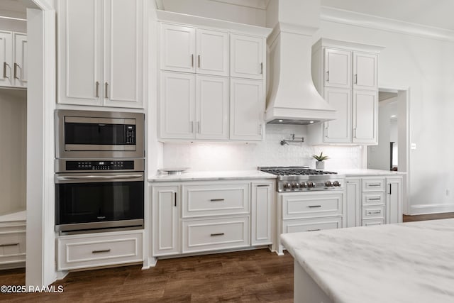 kitchen featuring white cabinetry, stainless steel appliances, custom exhaust hood, and backsplash