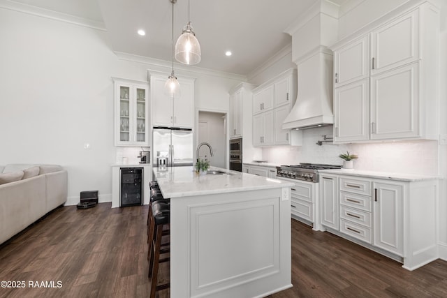 kitchen with a breakfast bar area, white cabinets, beverage cooler, stainless steel appliances, and a center island with sink