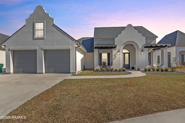 french provincial home with concrete driveway, roof with shingles, stucco siding, and a front yard