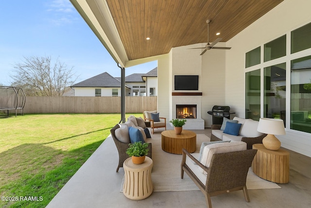 view of patio / terrace with a fenced backyard, an outdoor living space with a fireplace, grilling area, ceiling fan, and a trampoline