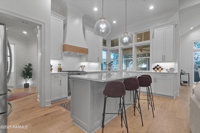 kitchen featuring backsplash, stainless steel appliances, light countertops, and custom range hood