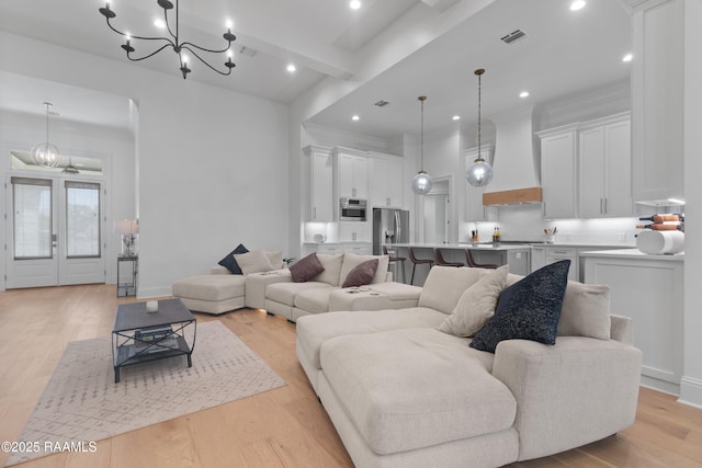 living room featuring beamed ceiling, crown molding, a chandelier, and light hardwood / wood-style floors