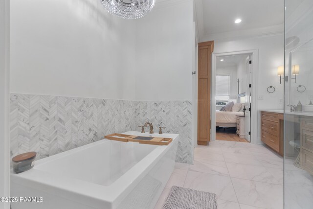 bathroom featuring connected bathroom, ornamental molding, a freestanding tub, marble finish floor, and vanity