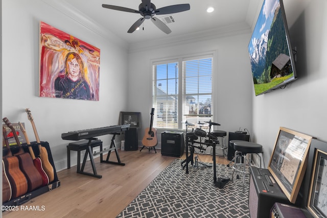 office area with wood finished floors, baseboards, visible vents, ceiling fan, and crown molding