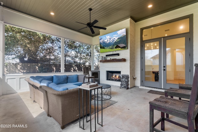 view of patio / terrace with a ceiling fan and an outdoor living space with a fireplace