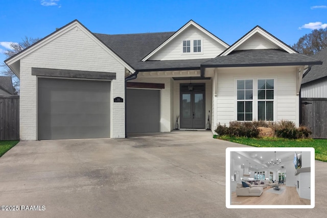 view of front of property with brick siding, french doors, an attached garage, and driveway