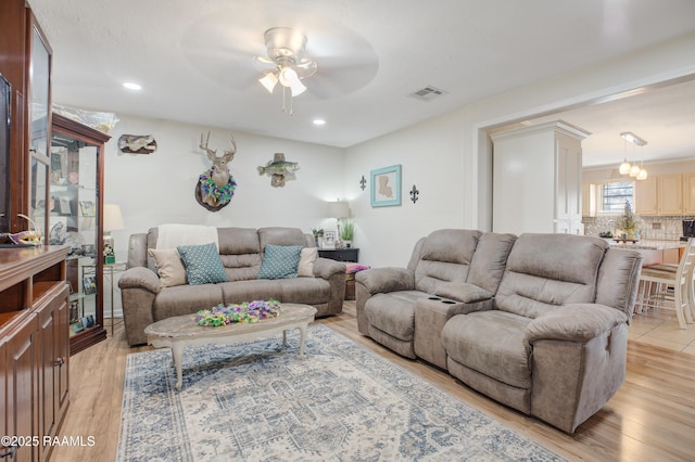 living room with ceiling fan, light hardwood / wood-style floors, and ornate columns