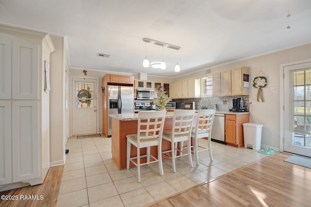 6903 W Congress, Duson, LA 70529 - kitchen featuring stainless steel appliances, ornamental molding, a kitchen island, a kitchen breakfast bar, and backsplash