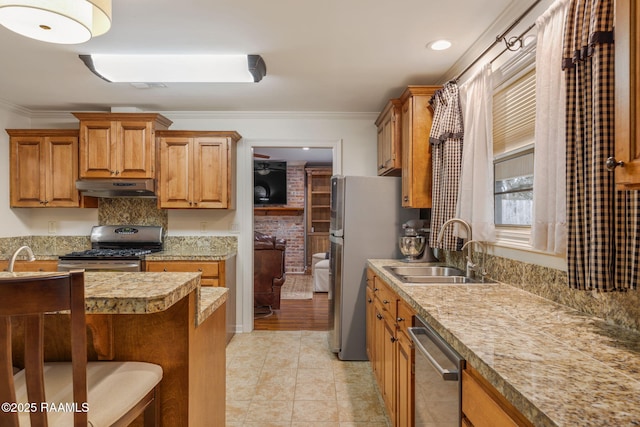 kitchen with under cabinet range hood, appliances with stainless steel finishes, a sink, and ornamental molding