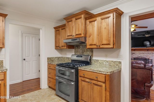 kitchen featuring brown cabinets, crown molding, a ceiling fan, double oven range, and under cabinet range hood