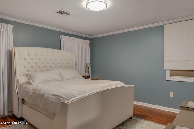 bedroom with ornamental molding, wood finished floors, visible vents, and baseboards