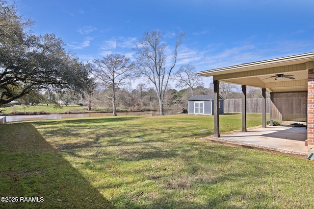 view of yard with a patio, a water view, ceiling fan, a shed, and an outdoor structure