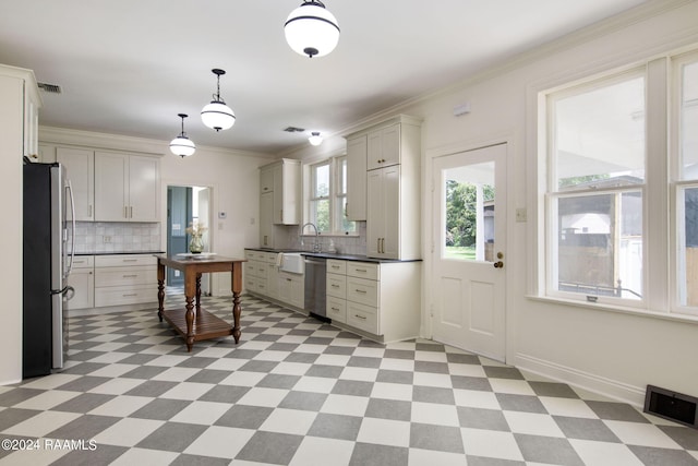 kitchen featuring crown molding, white cabinetry, hanging light fixtures, appliances with stainless steel finishes, and decorative backsplash