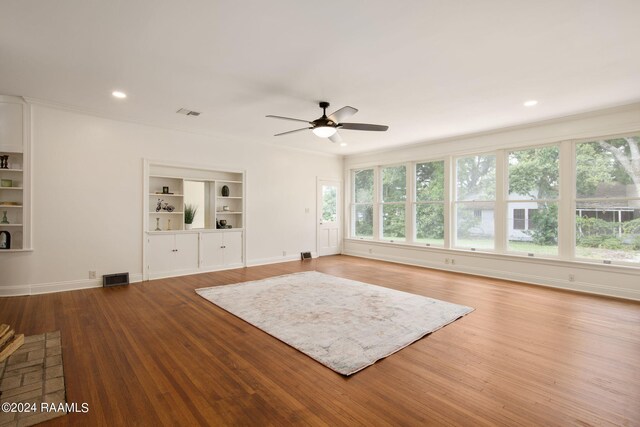 exercise room featuring plenty of natural light, built in features, ceiling fan, and light hardwood / wood-style flooring