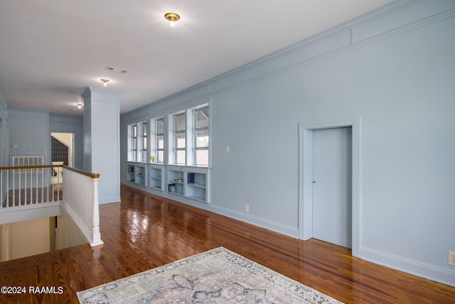 empty room with crown molding, hardwood / wood-style floors, and decorative columns