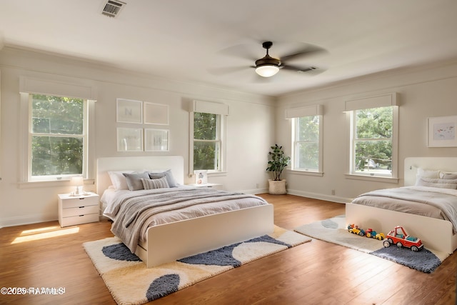 bedroom with ornamental molding, ceiling fan, and light wood-type flooring