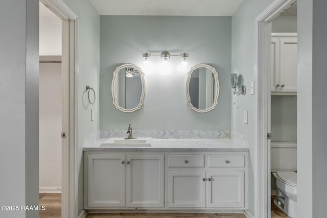 bathroom with vanity, toilet, and a textured ceiling