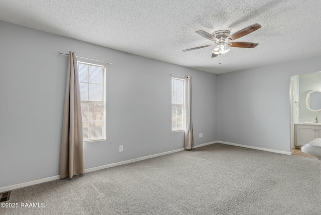 unfurnished bedroom with sink, ensuite bath, a textured ceiling, ceiling fan, and carpet